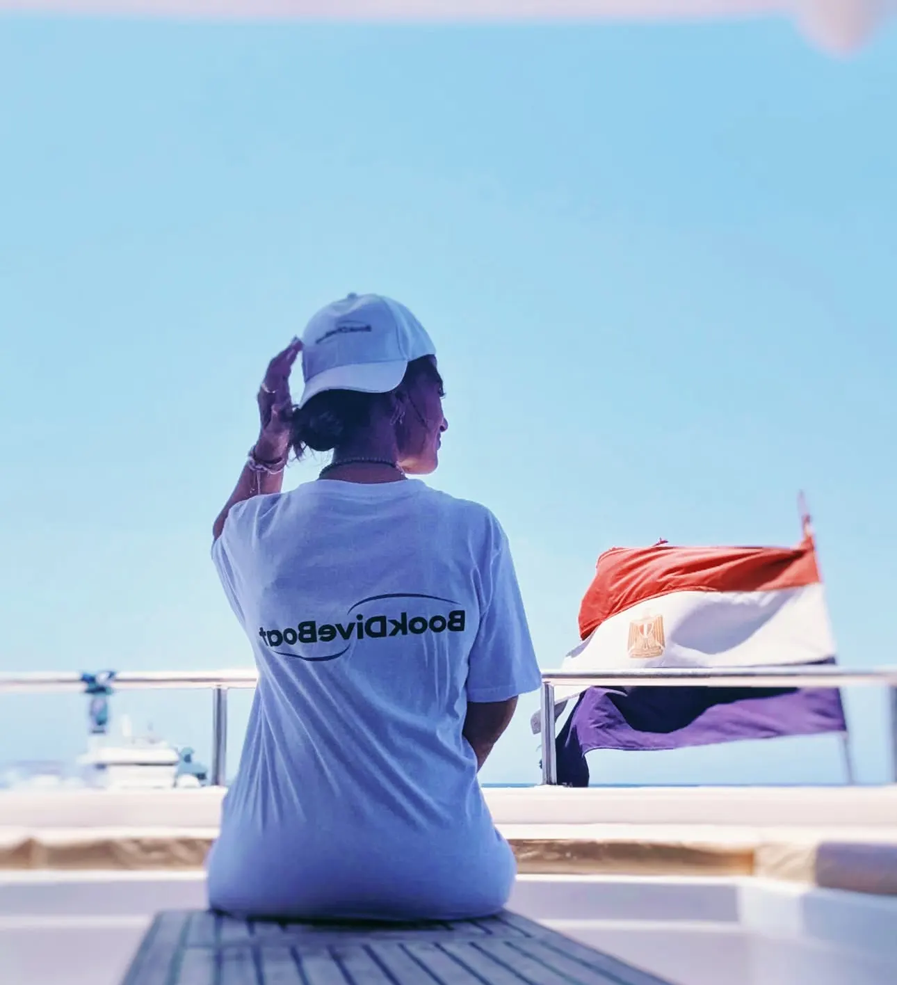 Malgosia, photographe sous-marine et ambassadrice BookDiveBoat, à bord devant un drapeau