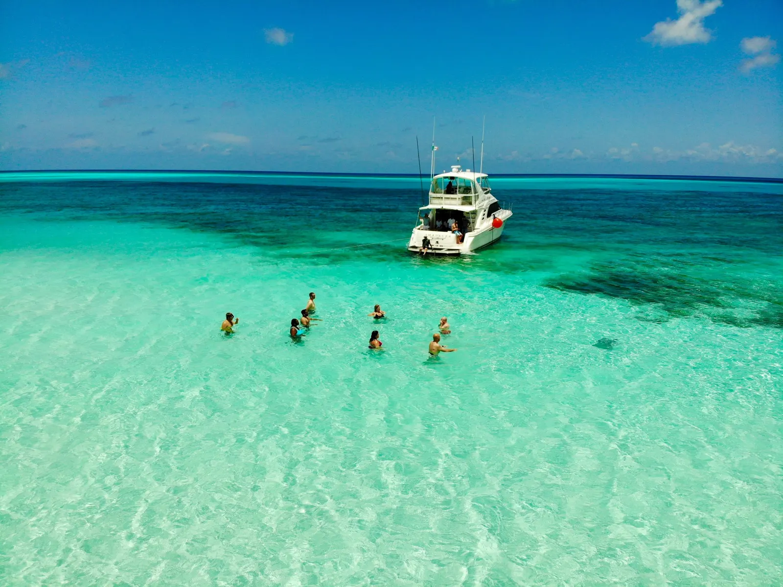 Baigneurs dans une eau turquoise, près d'un bateau