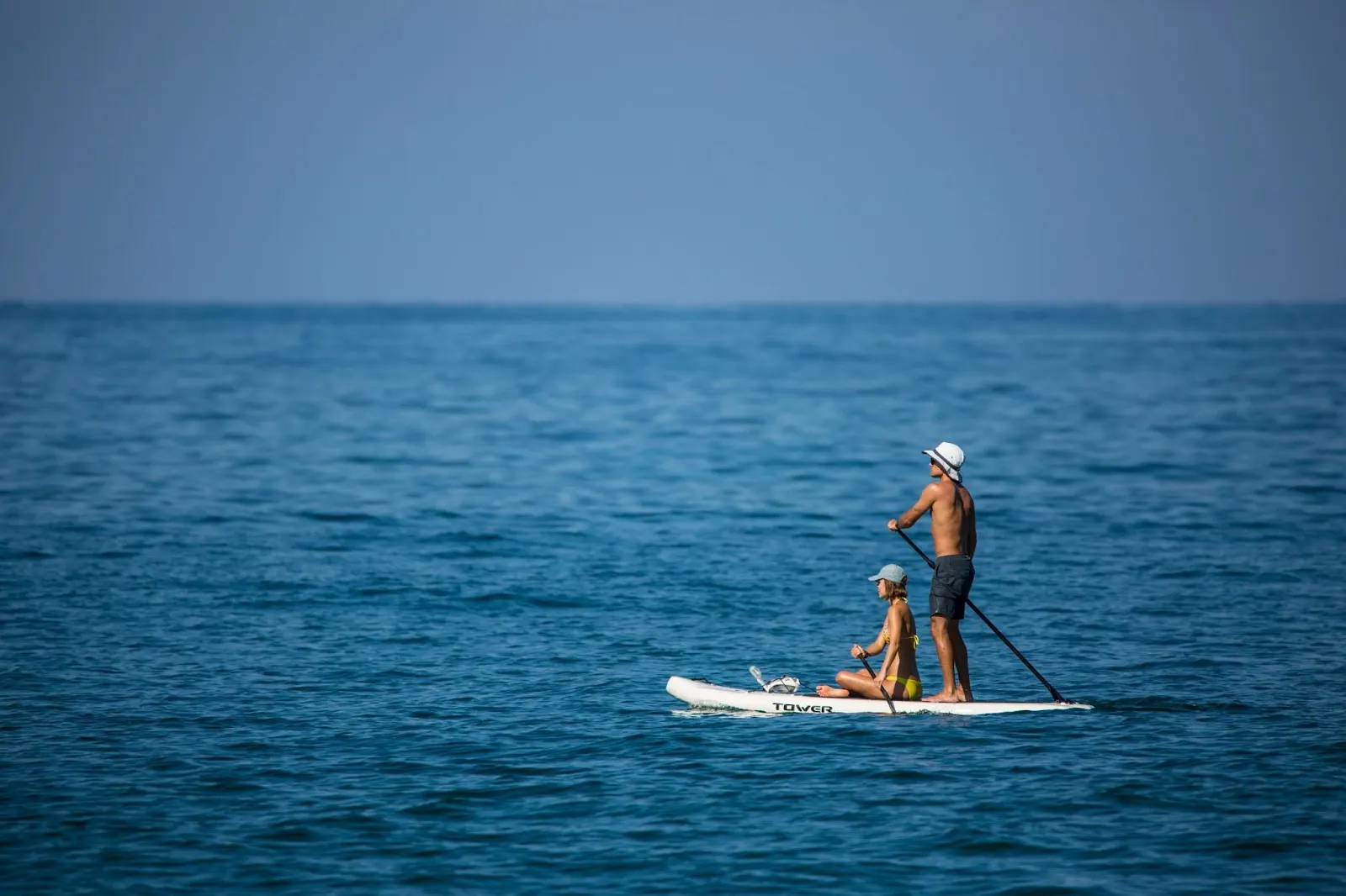Couple sur une planche de paddle en pleine mer