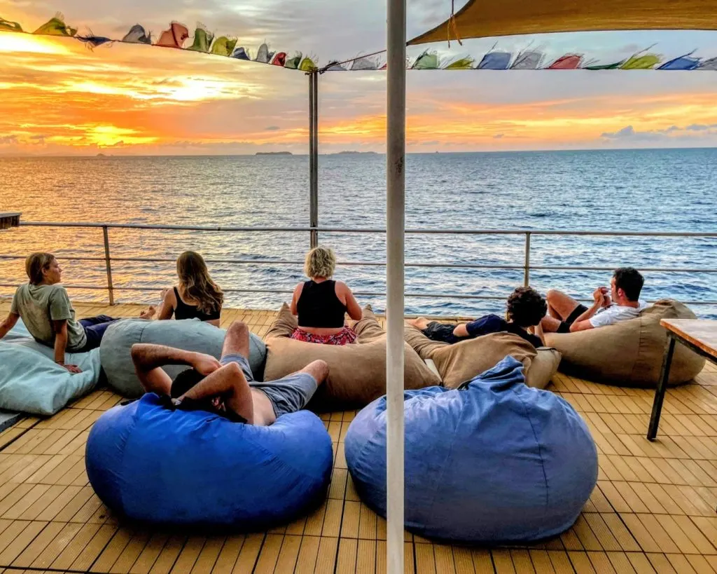 Passagers sur des poufs au coucher du soleil, sur le pont