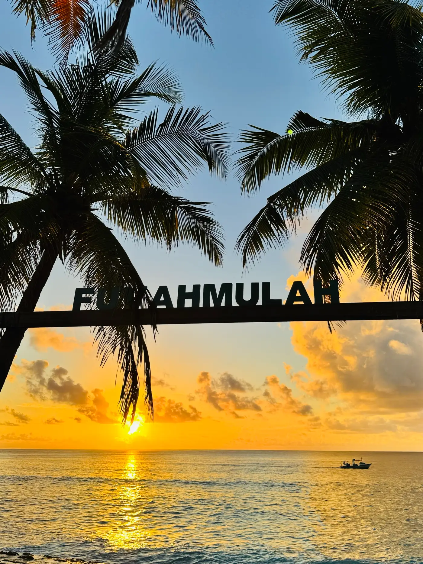 Lettres « Fuvahmulah » et palmiers devant le coucher du soleil