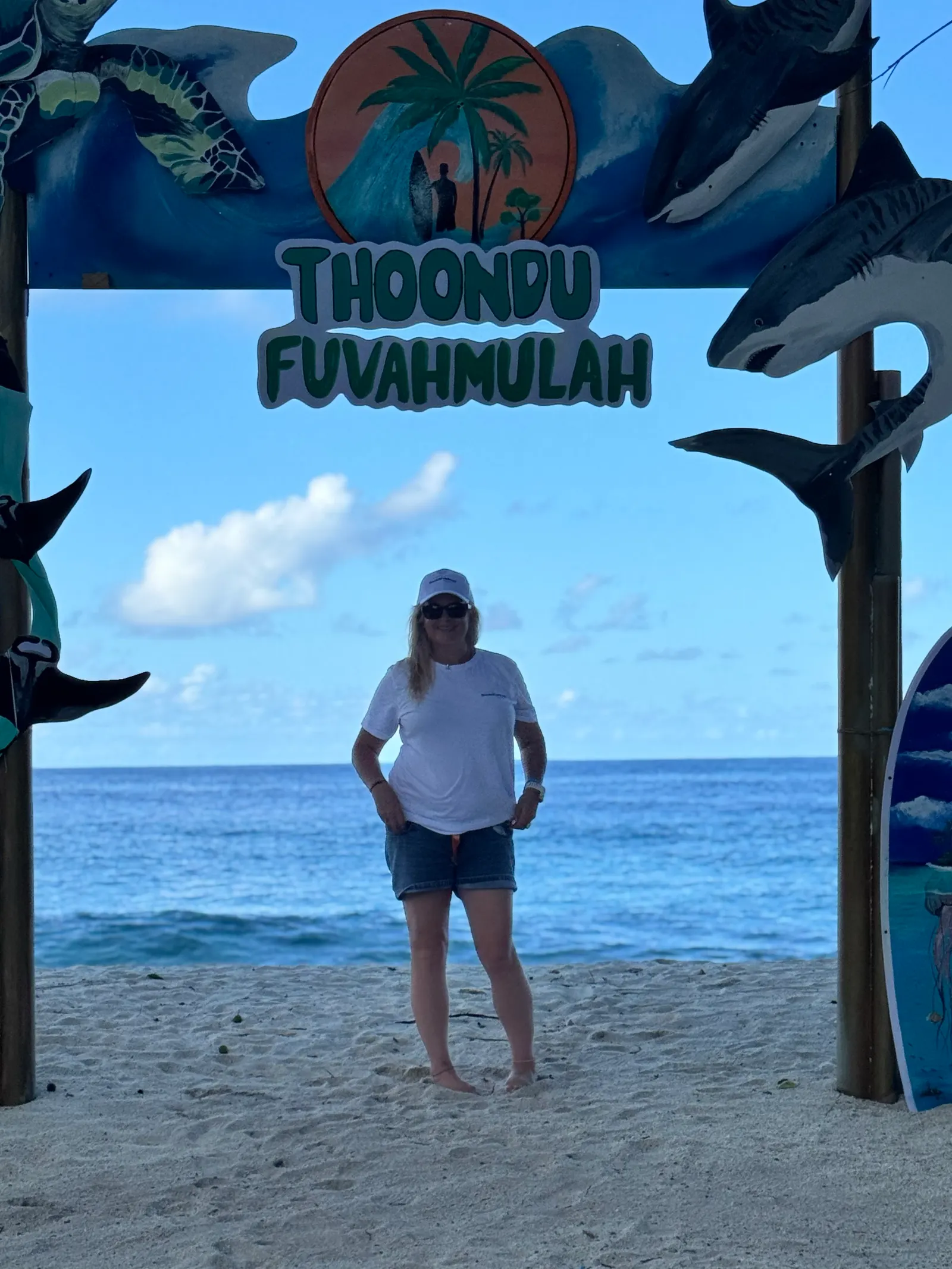 Sarah devant le panneau de la plage de Thoondu, l'océan derrière elle