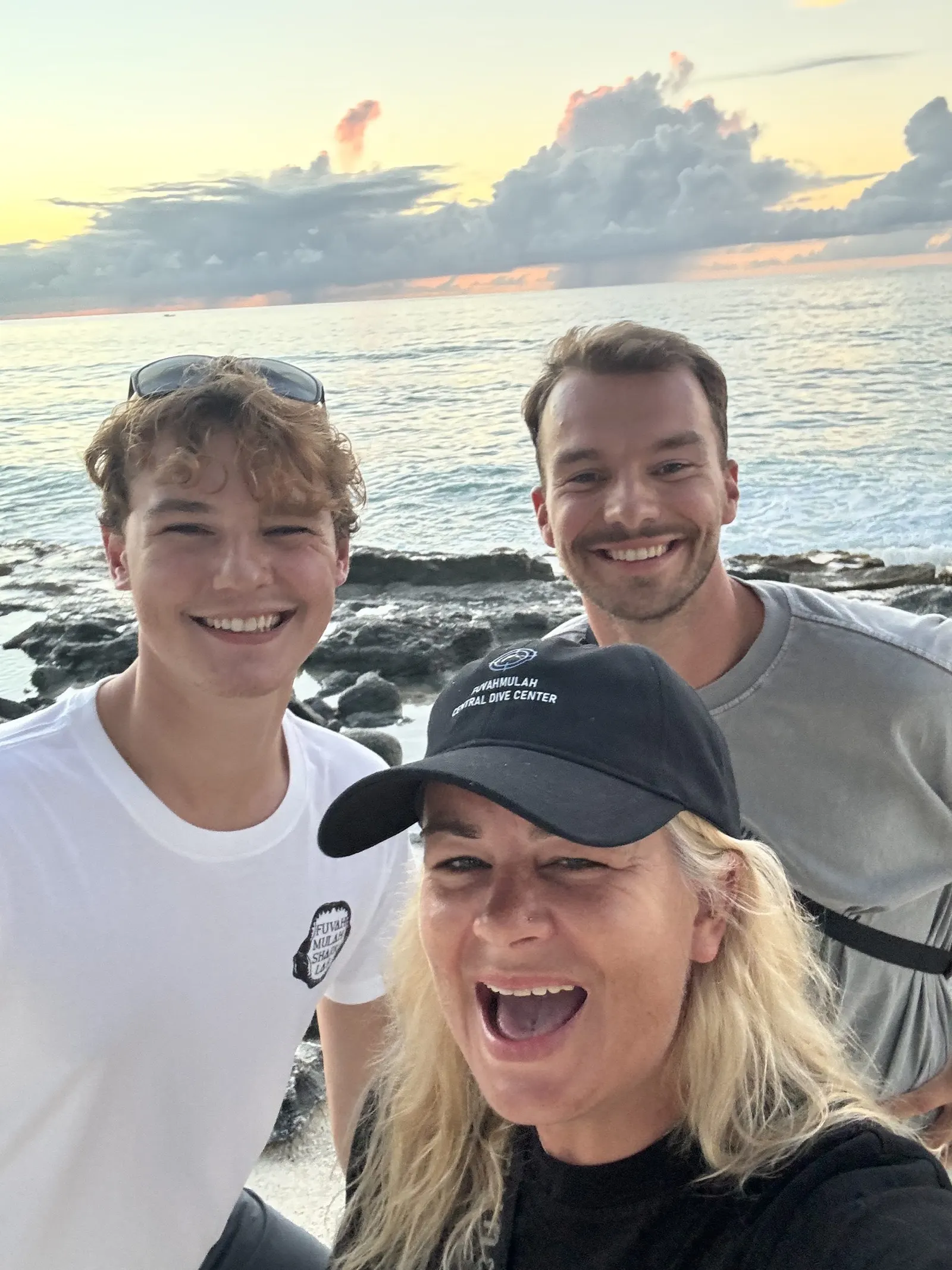 Trois plongeurs en selfie au coucher du soleil, sur le rivage